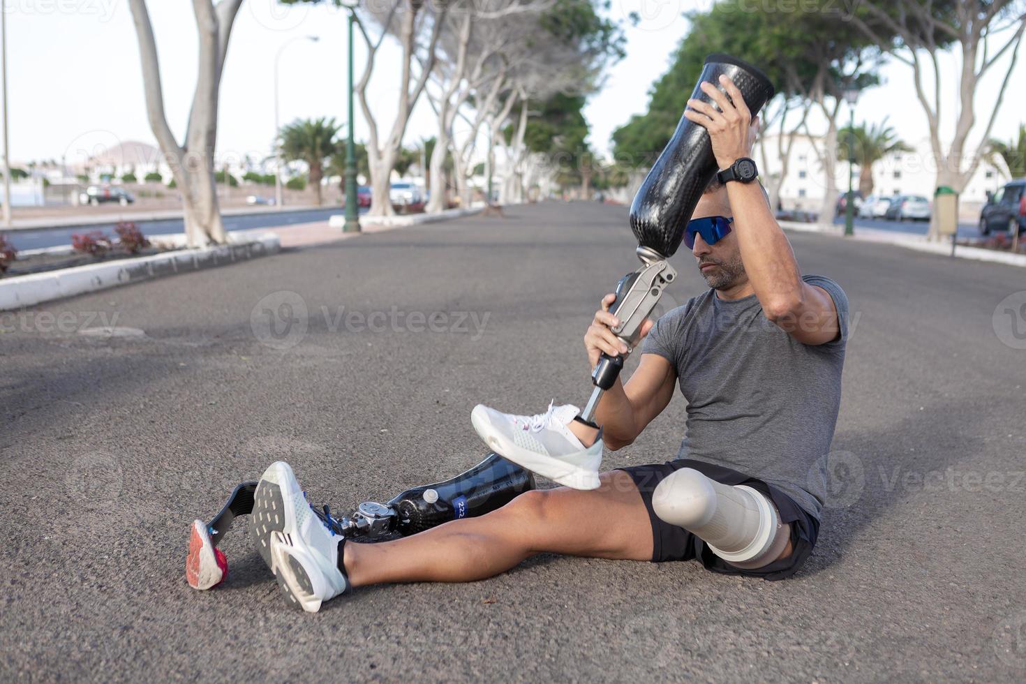 Sportsman changing leg prosthesis on road photo