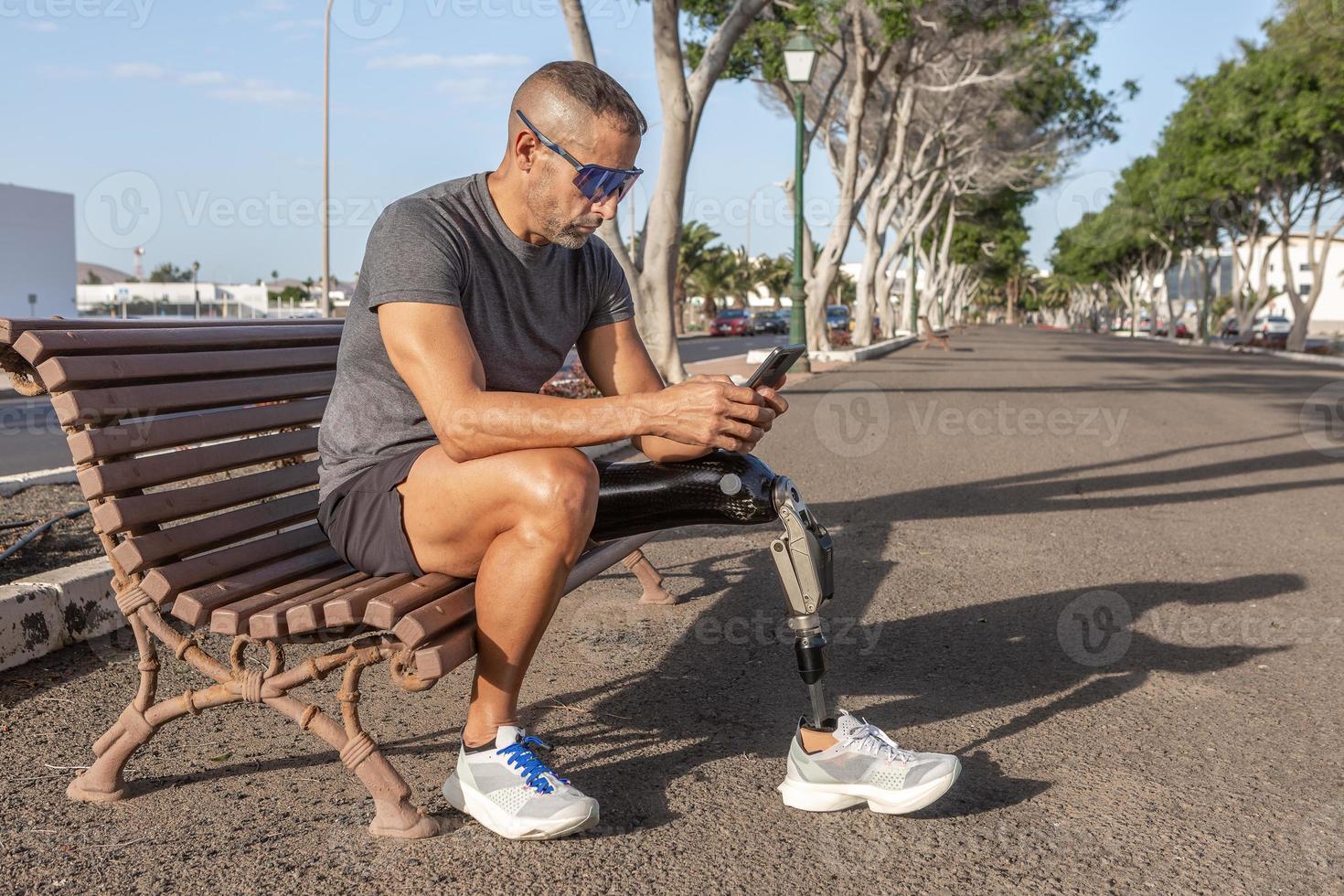 Male runner with disability using smartphone on street photo