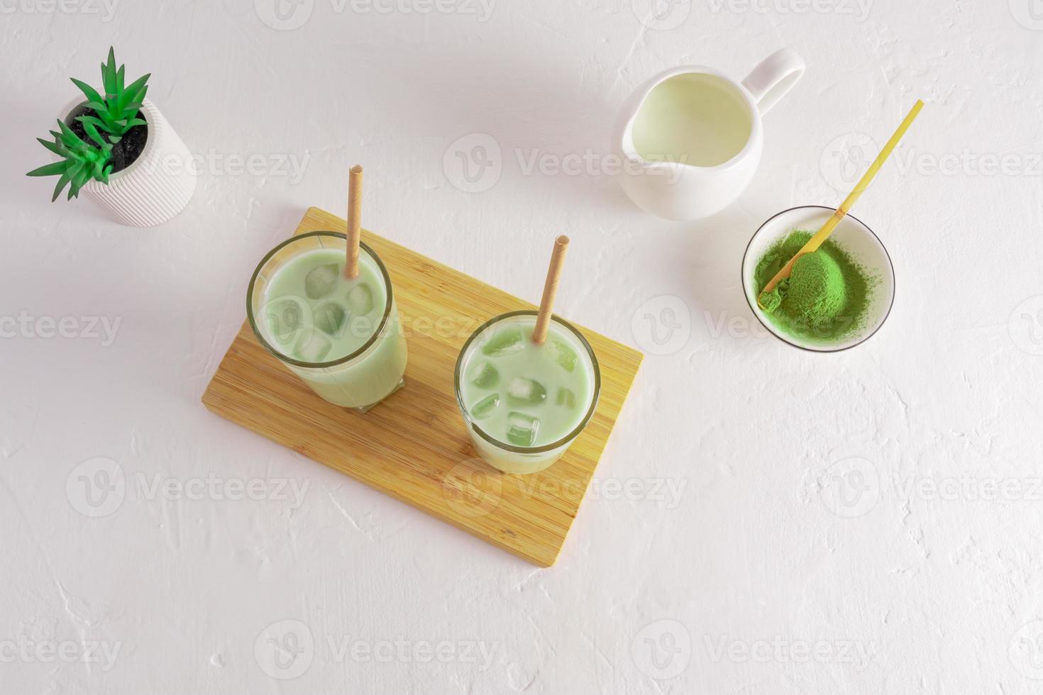 top view of two glasses of green tea matcha latte with ice cubes. a refreshing health drink. antioxidant, amino acids. white background. photo