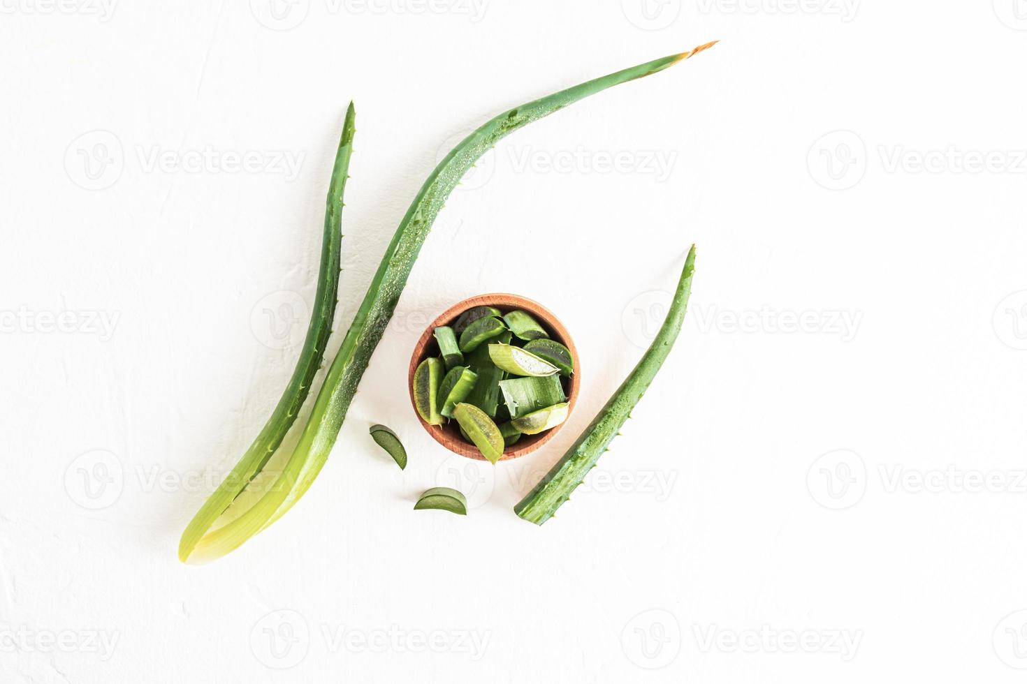 vista superior de un cuenco de madera con rodajas de la planta de aloe vera y hojas sobre un fondo blanco. estilo plano. planta medicinal. alternativa a la medicina foto