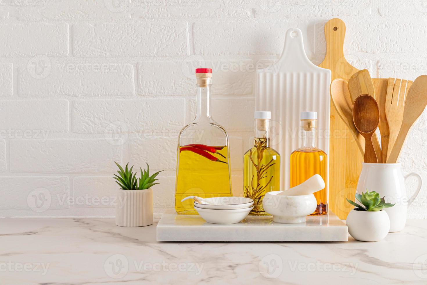 part of the kitchen countertop in a modern kitchen with various glass bottles with natural organic oils on a marble board. photo