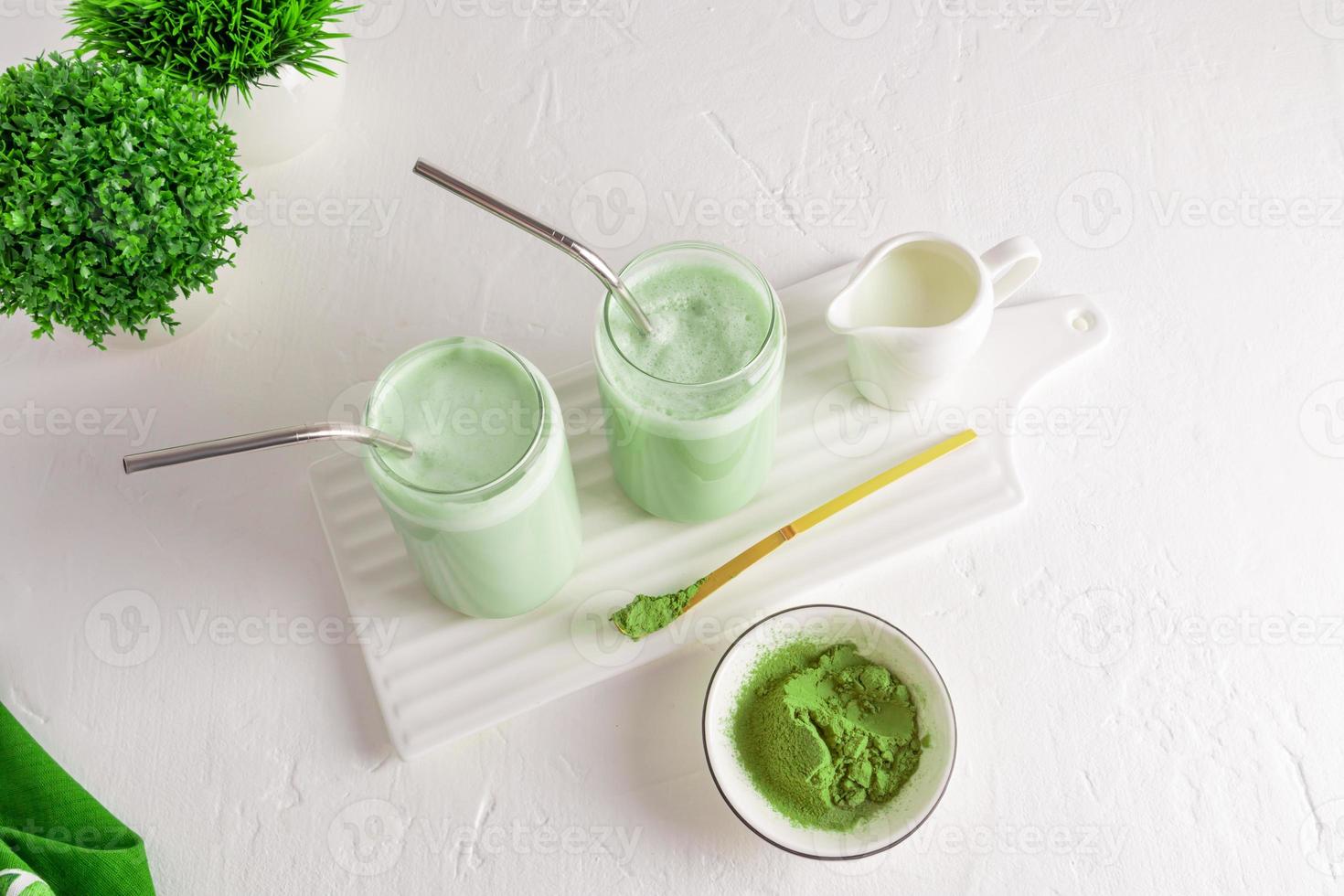 Iced tea matcha latte in two glass in the form of a beer can on a white ceramic board and awhite background with green plants. view from above. photo