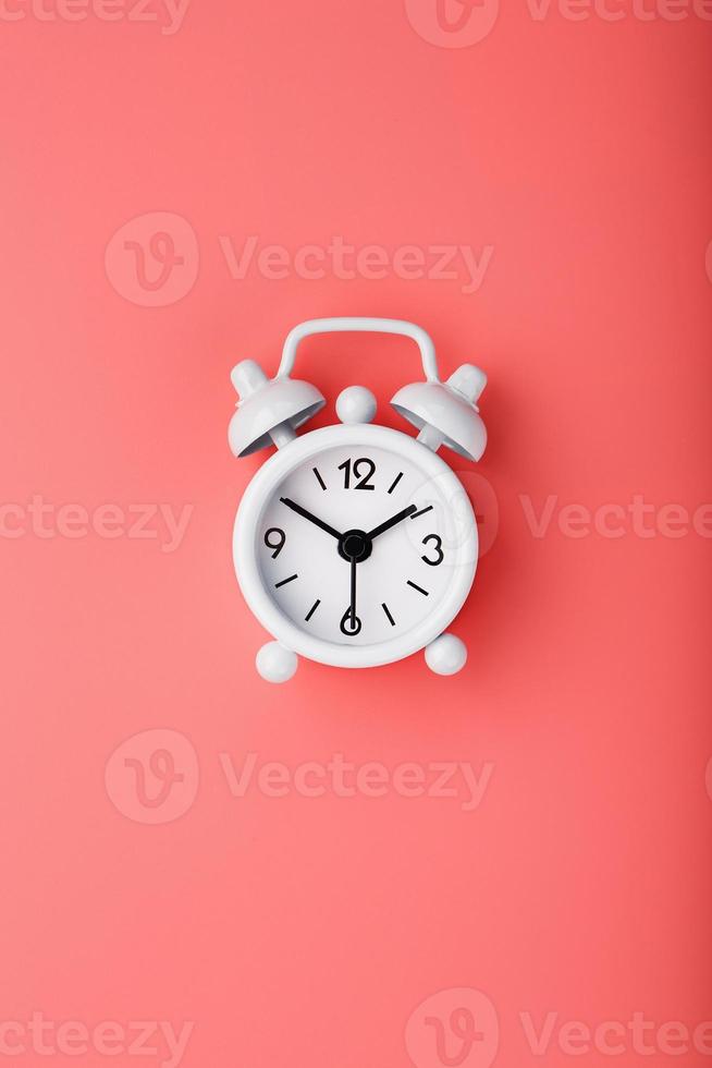 White retro alarm clock on pink background. Concept of time with free space for text. photo