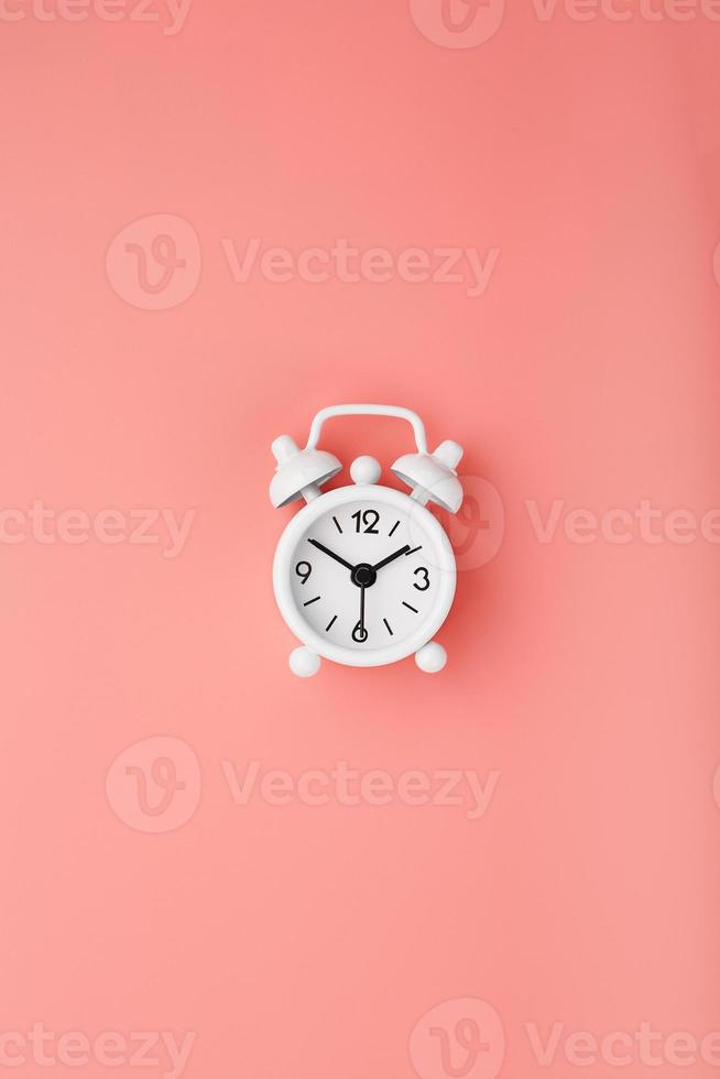 White retro alarm clock on pink background. Concept of time with free space for text. photo