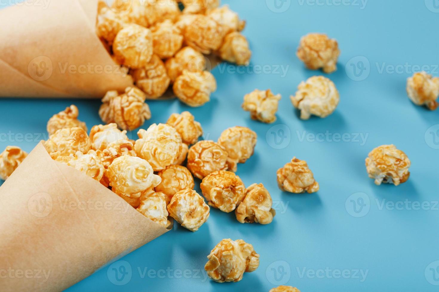 Caramel popcorn in a paper envelope on a blue background. photo