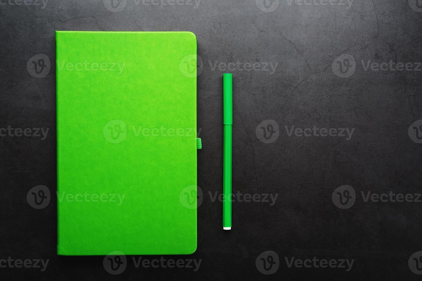 Green Notepad with a felt-tip pen on a black background, top view. photo