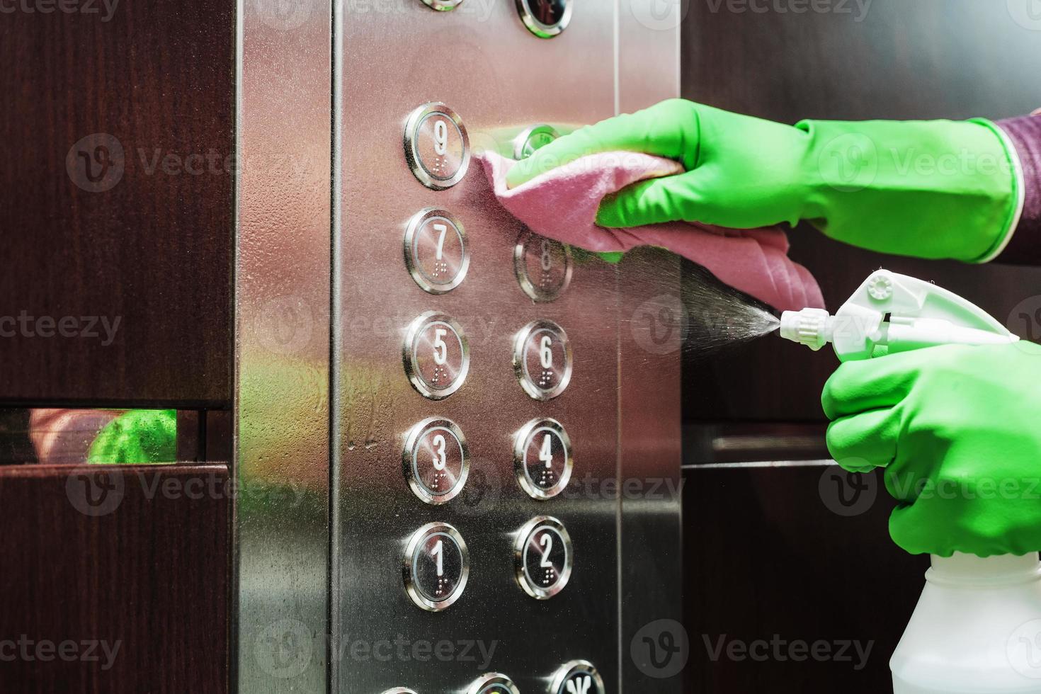 desinfección y cuidado higiénico con spray de alcohol en el botón del ascensor. foto