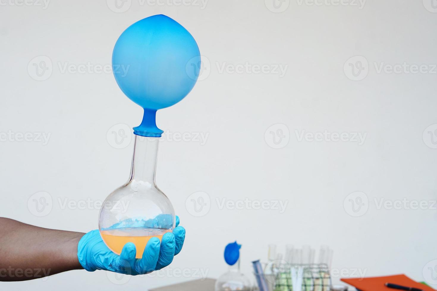 experimento científico, la mano sostiene una botella transparente con un globo azul inflado encima de la botella. El experimento sobre la reacción del aire o el gas. Mediante el uso de sustancias químicas. concepto, educación científica foto