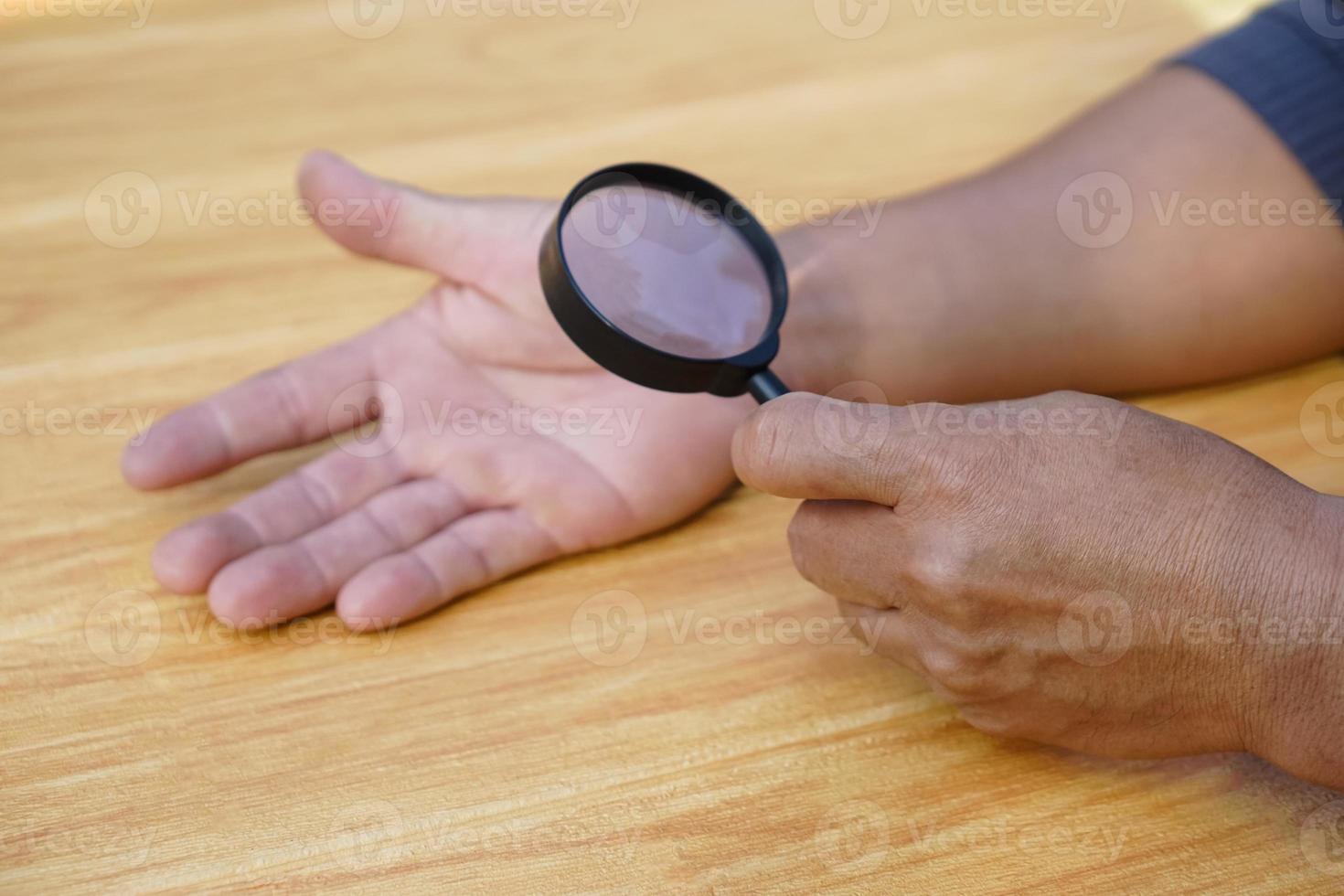 Closeup hand holds magnifying glass to inspect palm lines. Concept, palmistry, astrology. Foretelling, mystery, magic, fortune, fate. Prediction for future life , events.  Palmist predicting. photo