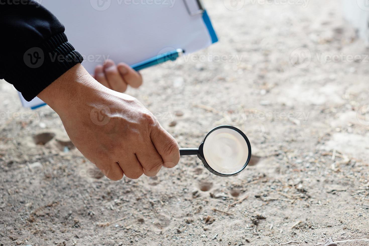 Closeup hand holds magnifying glass to explore tiny insects in holes on ground. Concept, examine, explore, research nature or biological organisms. Study about insects behavior. Science tool. photo