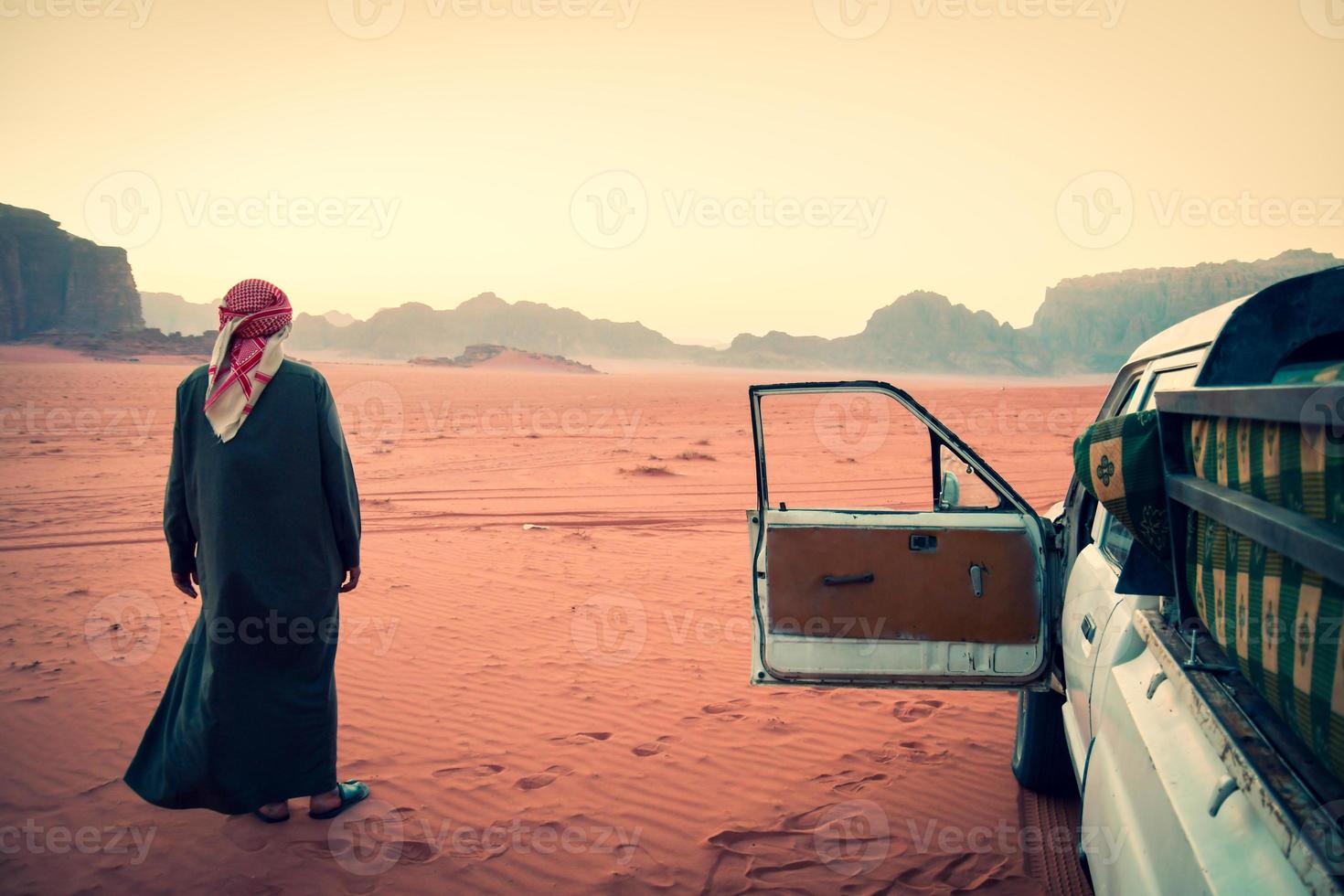 el organizador de la gira del conductor beduino se encuentra en el desierto de wadi rum en un vehículo con tracción en las cuatro ruedas después del atardecer. visite jordan tours en la famosa reserva de wadi rum oriente medio foto