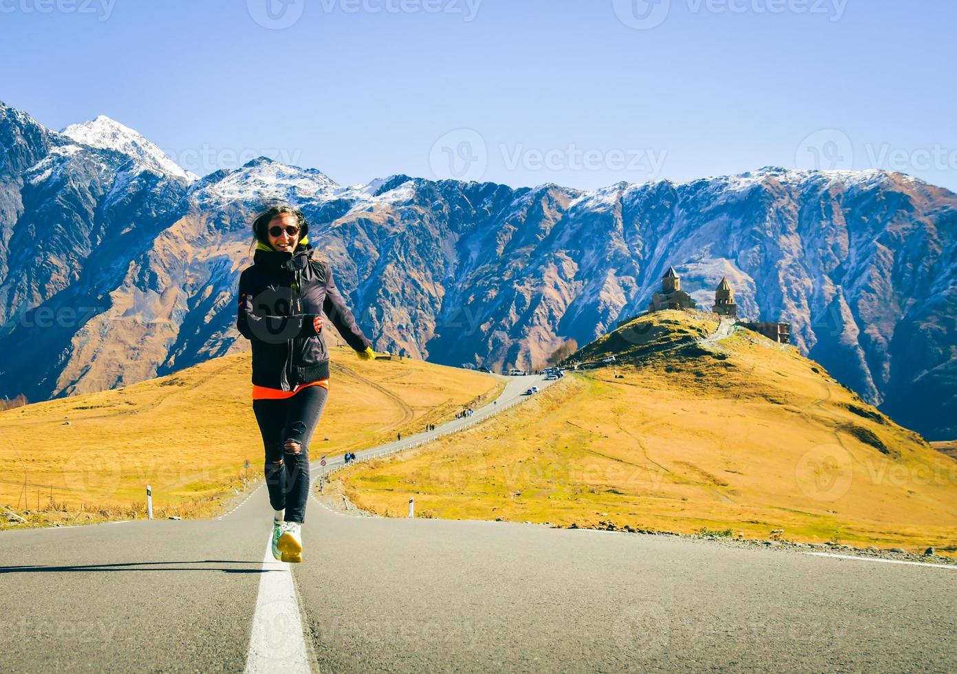 Tourist run by Gergeti trinity church in Georgia. Famous Gergeti Trinity Tsminda Sameba Church In Early Winter Landscape. Beautiful Georgian Landscape In fall, autumn Early Winter photo