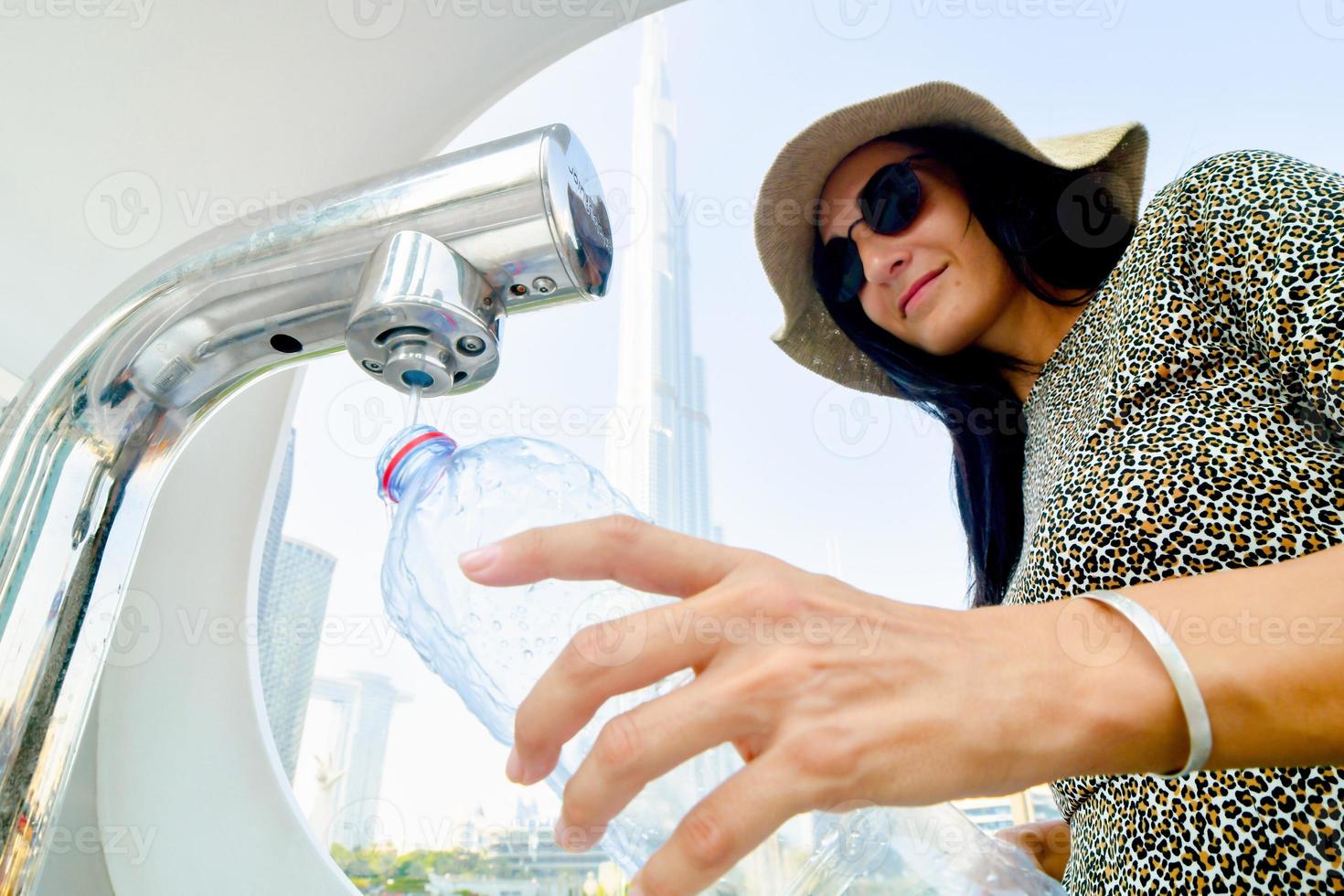 Dubai, UAE, 2022 - tourist woman use water refill machines in public places for tourist. Save earth save water and reduce plastic concept photo