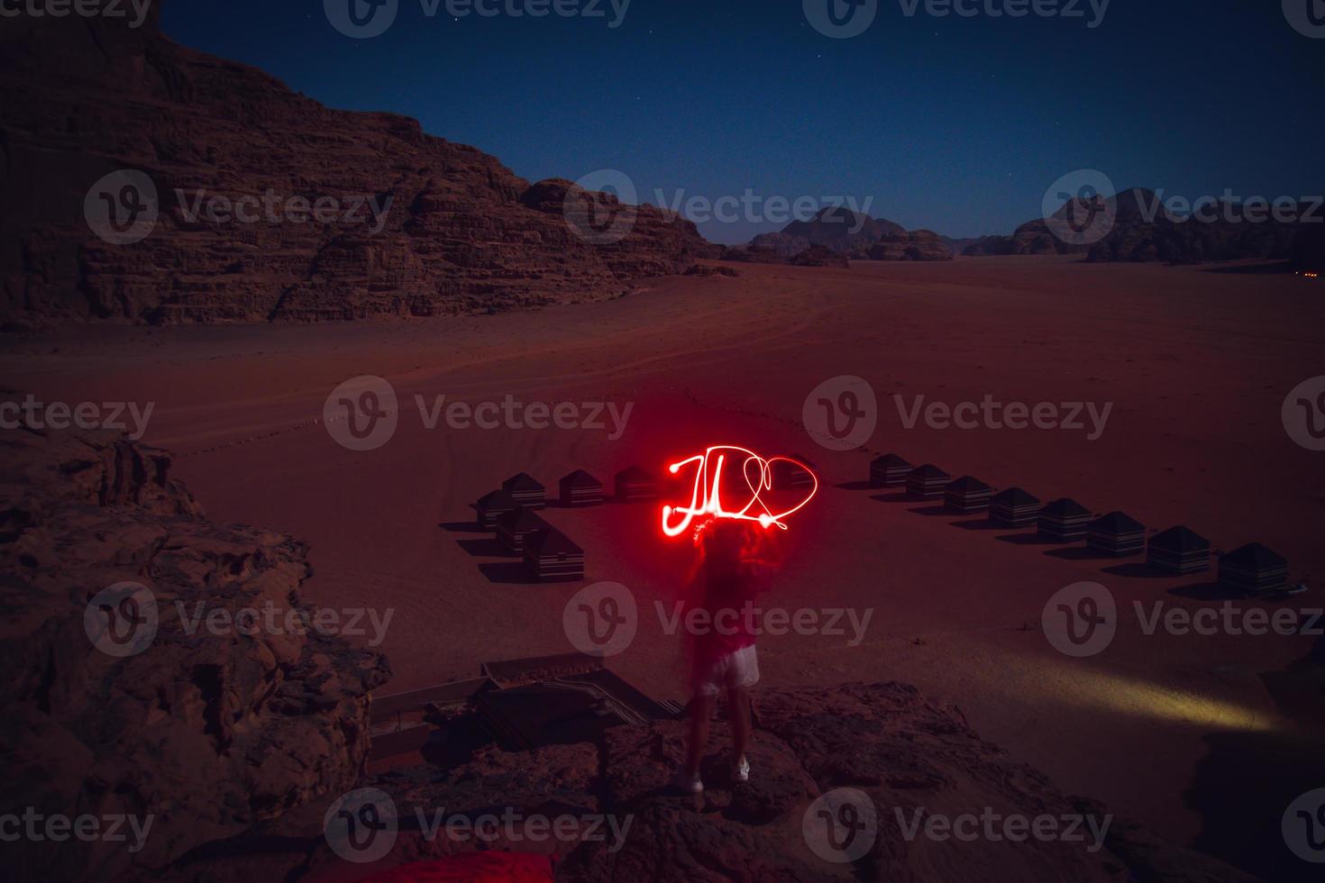 Traveler dreamer adventurer in wadi rum desert at night light painting word JO as Jordan with heart. Travel explore Jordan adventure concept photo
