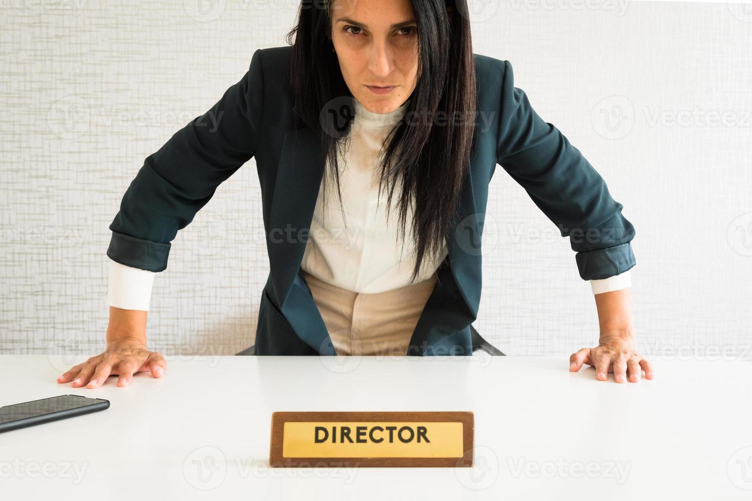 joven mujer de negocios morena caucásica directora en la oficina levántate cara enojada muestra presión mira la cámara pov. director enojado en la oficina furioso desde el asiento en su punto de vista foto