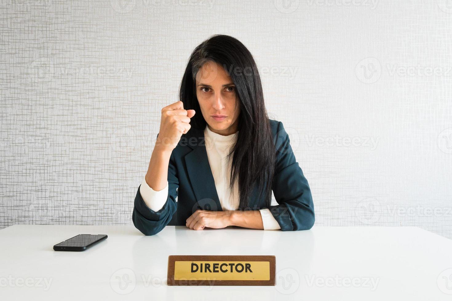 joven linda mujer de negocios morena caucásica directora en la oficina muestra el puño a la cámara en el trabajo para el empleado resentido enojado mirada seria a la cámara. empleado pov foto