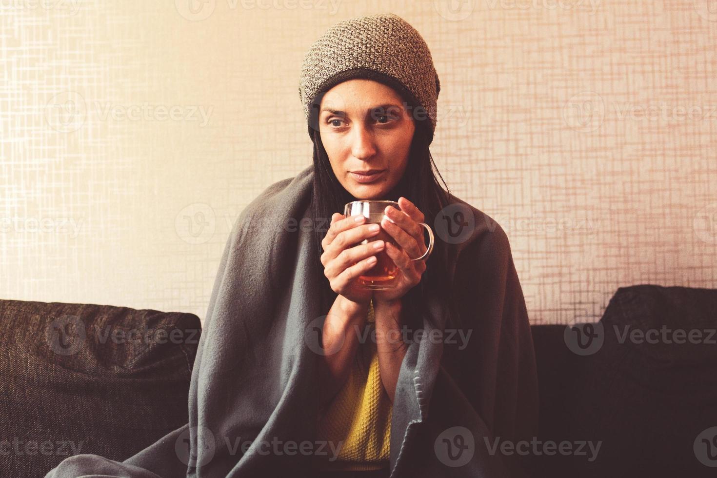 Caucasian Worried sad woman sits under blanket on sofa with cup of tea, Rising costs in private households for gas bill due to inflation and war, Energy crisis. Save gas costs xmas photo