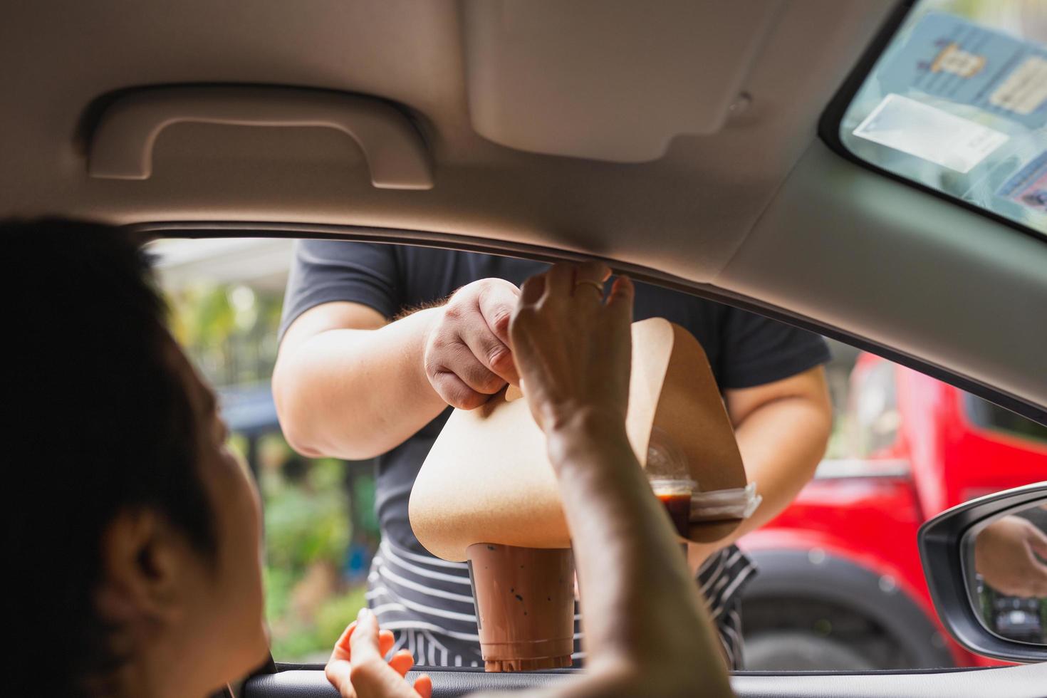 camarero entrega bebida de café helado al cliente en el coche. foto