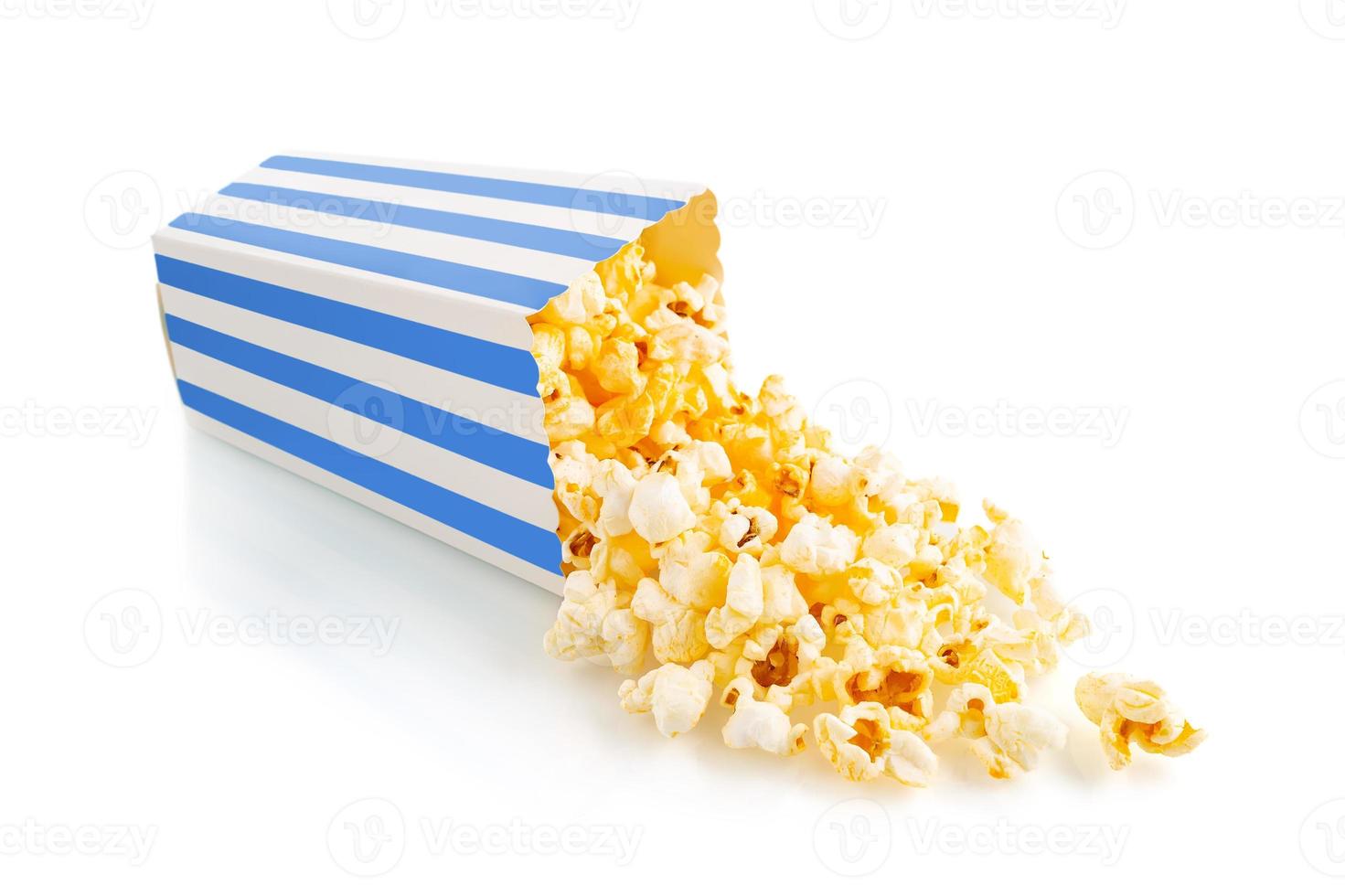 Tasty cheese popcorn falling out of a blue striped carton bucket, isolated on white background photo