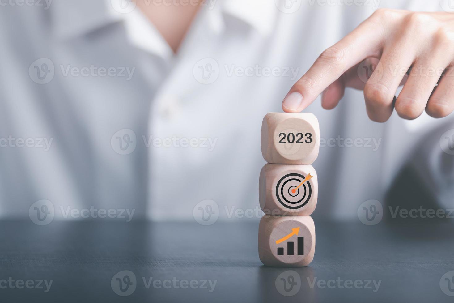 New Year 2023 Beginning Concept,Business Growth Graph and Success Goals,progress in development, financial efficiency and investment, Human hand pointing at wooden block placed on the table photo