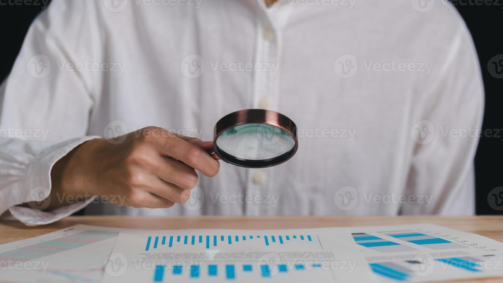 Businessman holding a magnifying glass,Audit Document Concepts, quality assessment management With a checklist, business document evaluation process, market data report analysis and consulting photo