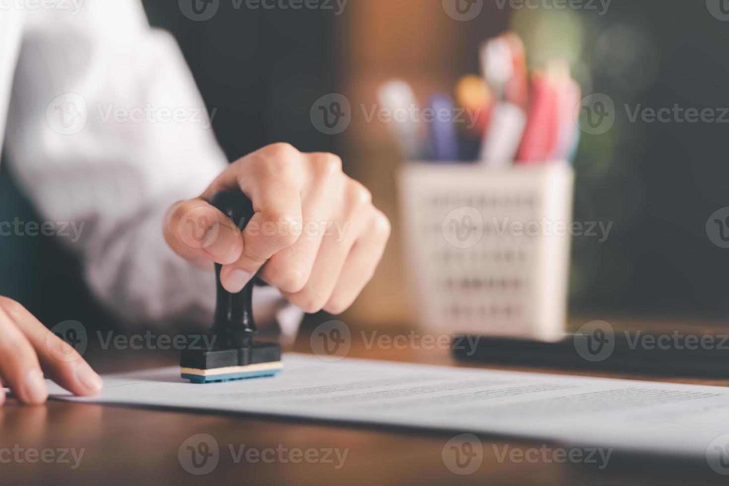 Businessman validates and manages business documents and agreements, signing a business contract approval of contract documents confirmation or warranty certificate,approval stamp photo