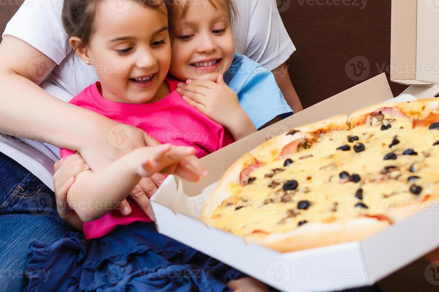 Portrait of happy family eating pizza while sitting on sofa at home photo