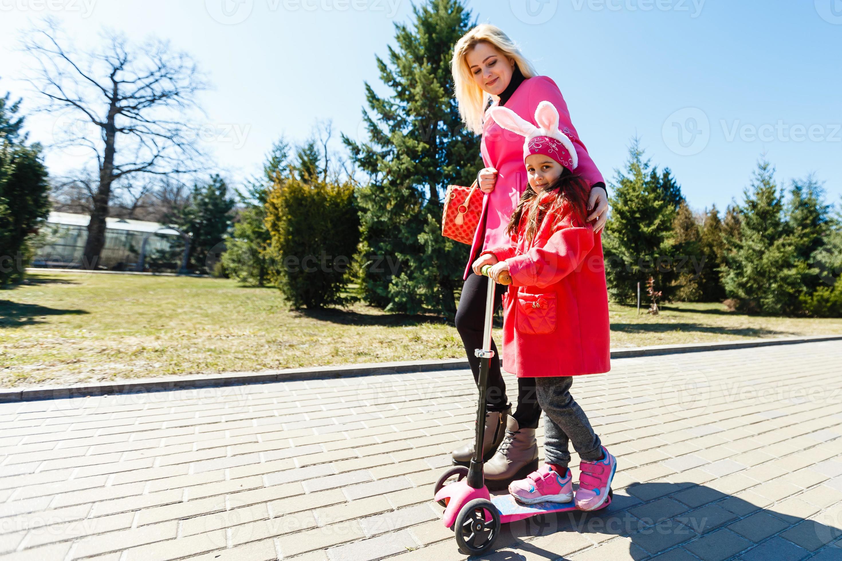 Child riding scooter on way back to school. Little girl playing