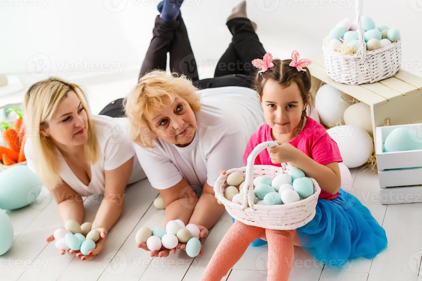 Getting ready to Easter. Lovely little girl holding an Easter egg and smiling with decoration in the background photo
