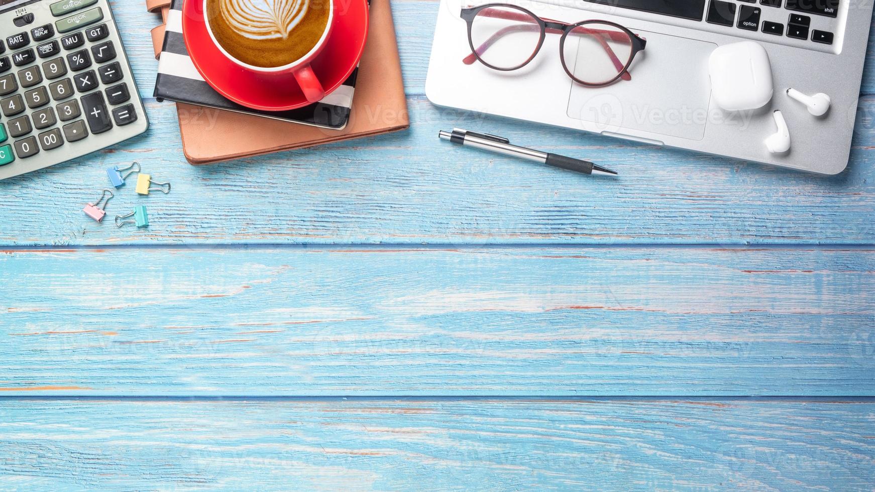 Laptop computer, calculator, notebook, pen, earphone and cup of coffee on wooden desk, Top view flat lay with copy space. photo