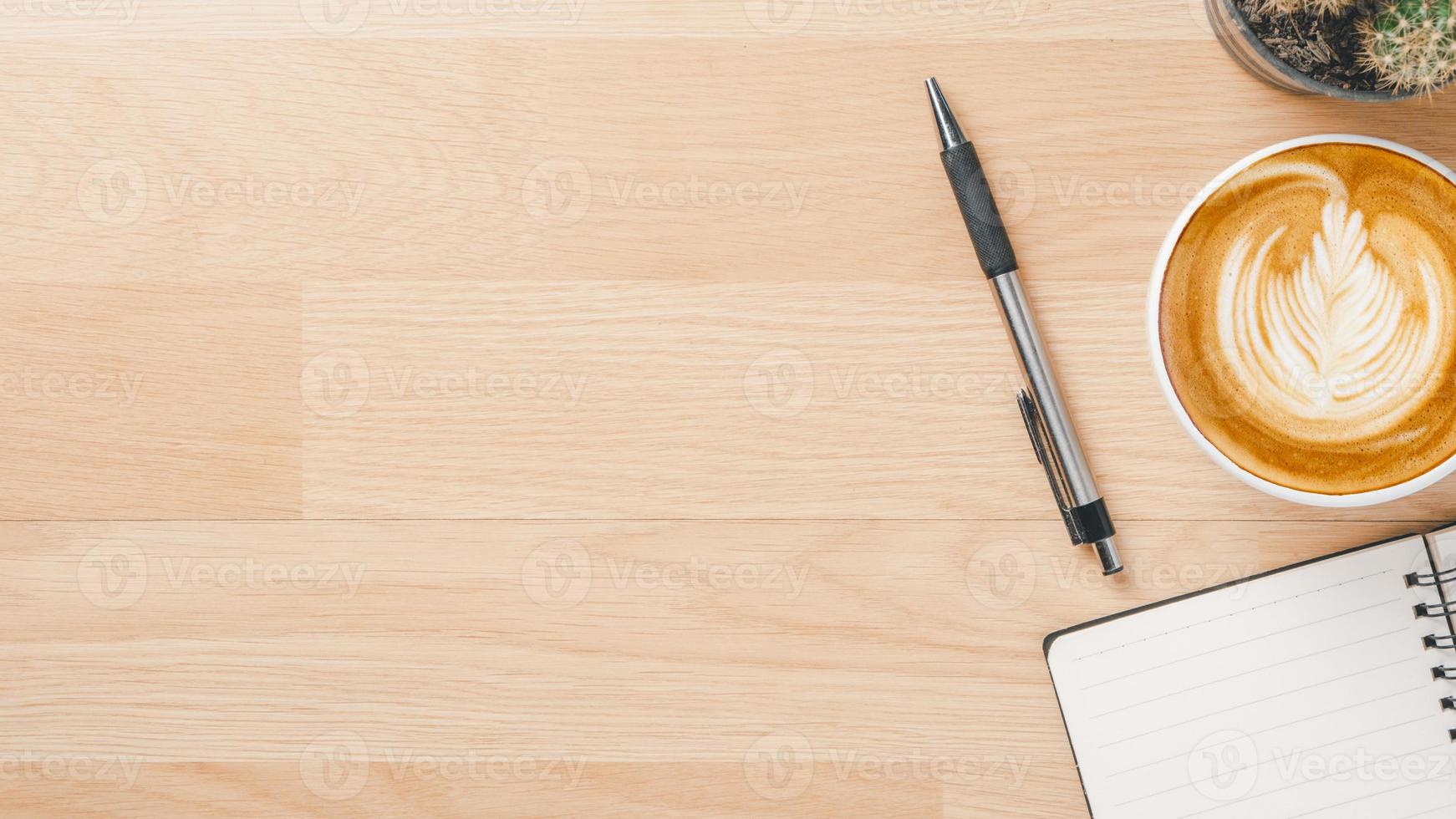 espacio de trabajo de escritorio de oficina con cuaderno, bolígrafo y taza de café, vista superior plana con espacio para copiar. foto