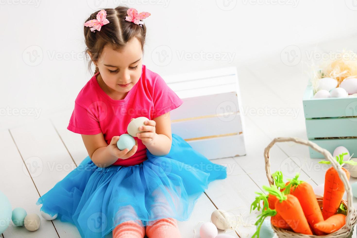 Getting ready to Easter. Lovely little girl holding an Easter egg and smiling with decoration in the background photo