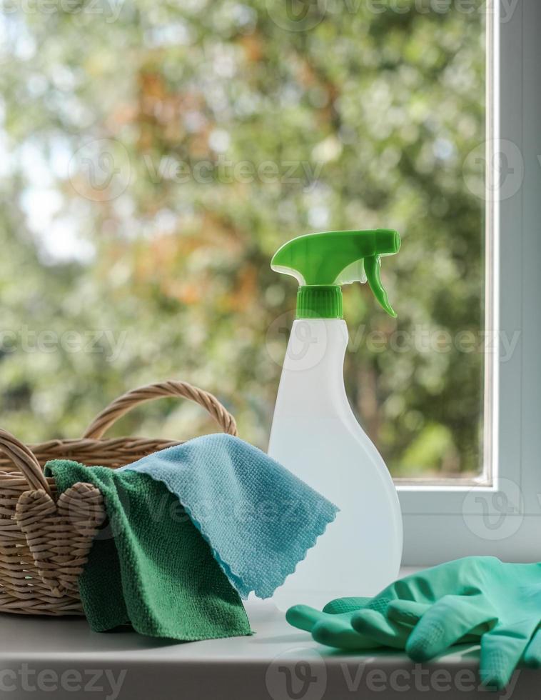 agente de limpieza, toallitas y guantes de goma en una cesta en el alféizar de la ventana. concepto general de limpieza foto