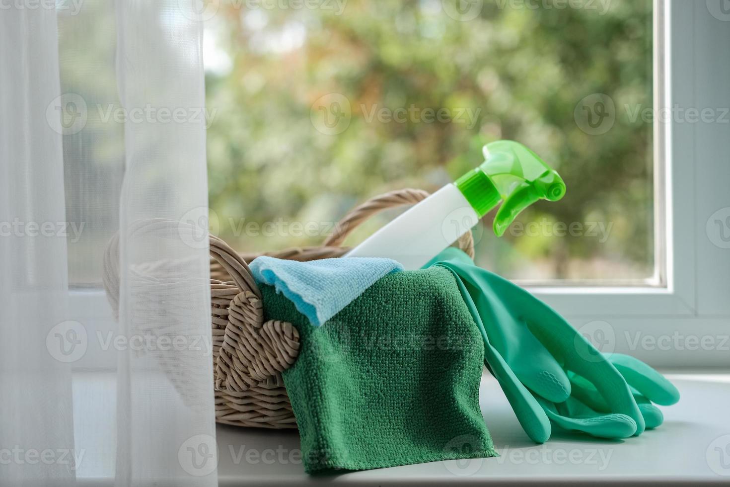 Cleaning agent, wipes and rubber gloves in a basket on the windowsill. General cleaning concept photo