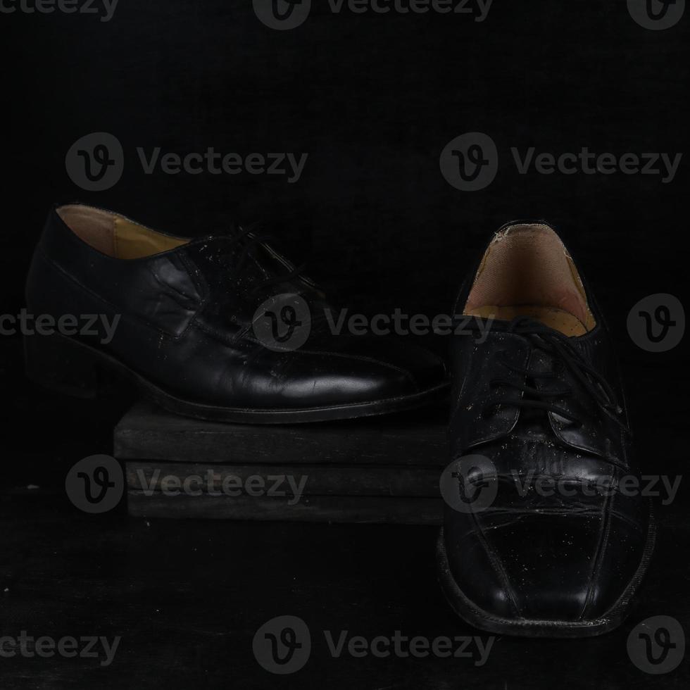 Pair of black male classic shoes on black background. Dusty shoes photo