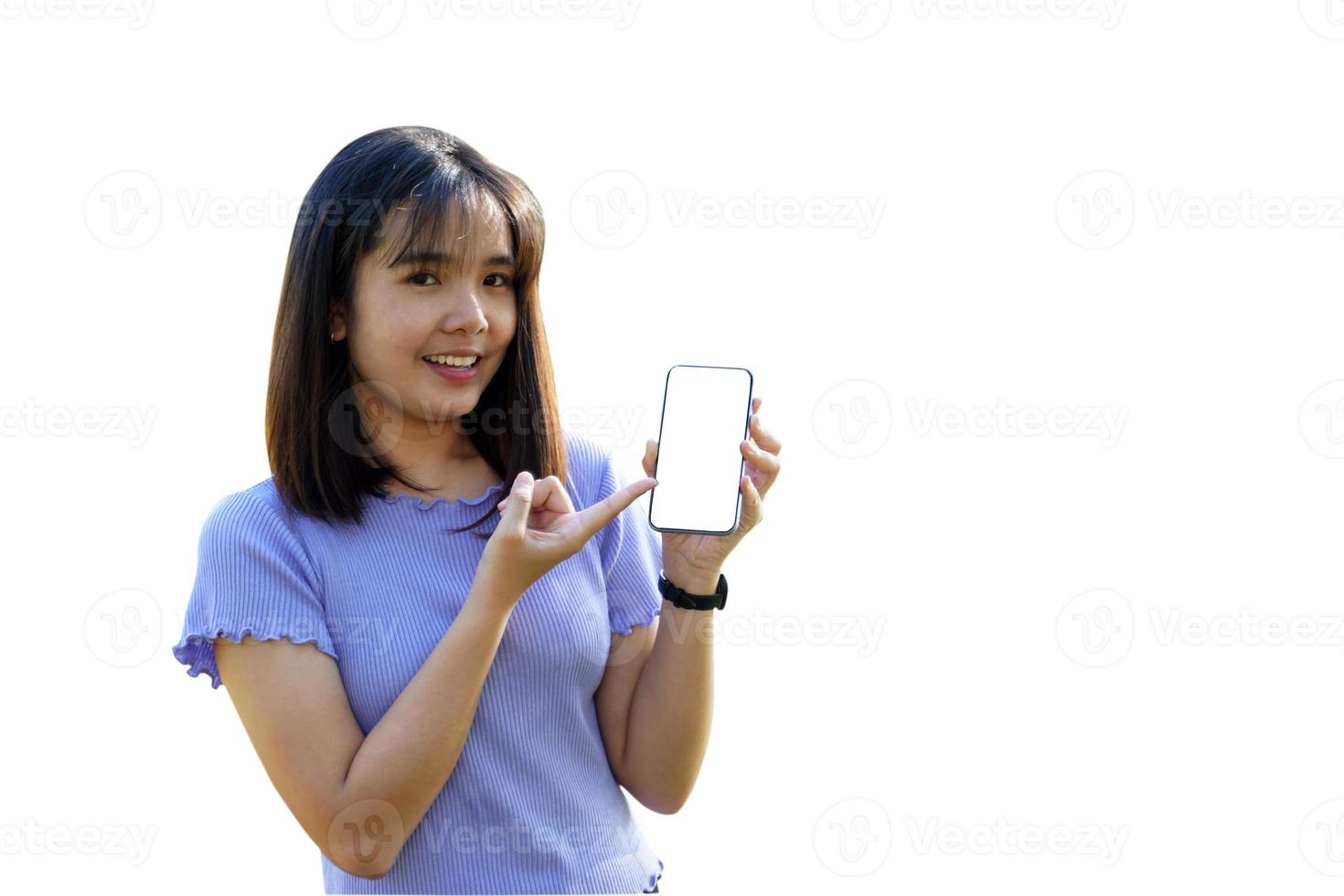 Smiling Asian woman playing and update new applications. Her hand pointed at the phone with blank screen workspace area chatting on white background. Soft and selective focus. photo