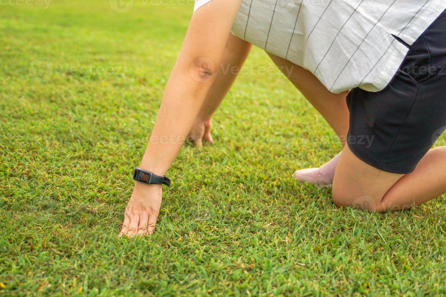 Asian woman wearing smart watch She was leaving the starting line for a run on the grass. In the concept of initiation, goal, goal, leisure activity, outside, exercise. photo