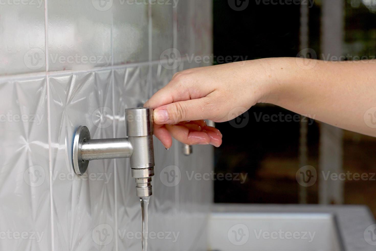 Asian woman opening faucet to wash hands Clean before and after touching food. Soft and selective focus. photo
