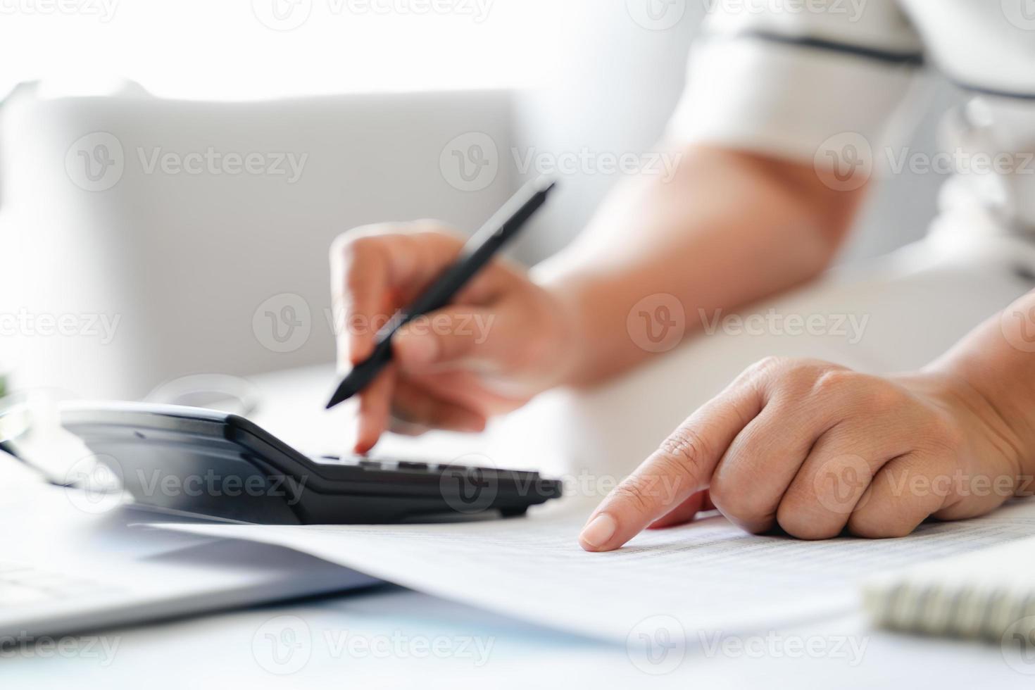 Woman is calculating annual tax with calculator and filling form of Individual Income Tax Return. Season to pay Tax and Budget planning concept. photo