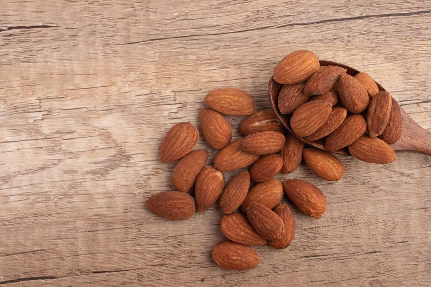 Salted almonds in wooden spoon on wooden background photo