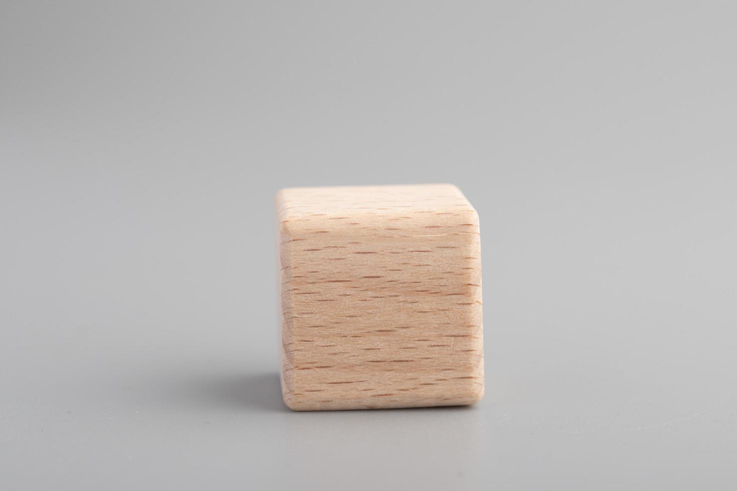 Simple empty wooden dice, one blank cubes made of wood with one central element, gray background. Copy space, logo space in the middle. photo