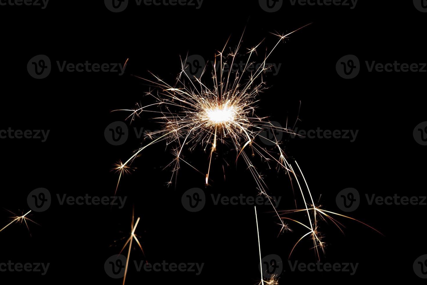 Burning sparkler isolated on black background. Fireworks theme. Light effect and texture. photo