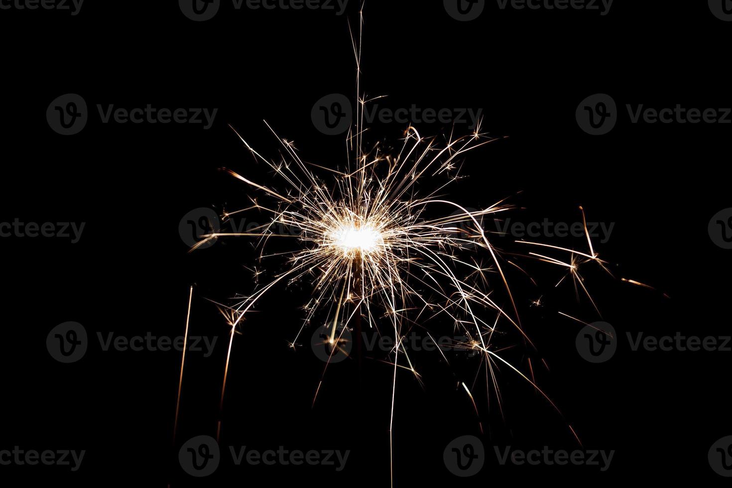 Burning sparkler isolated on black background. Fireworks theme. Light effect and texture. photo