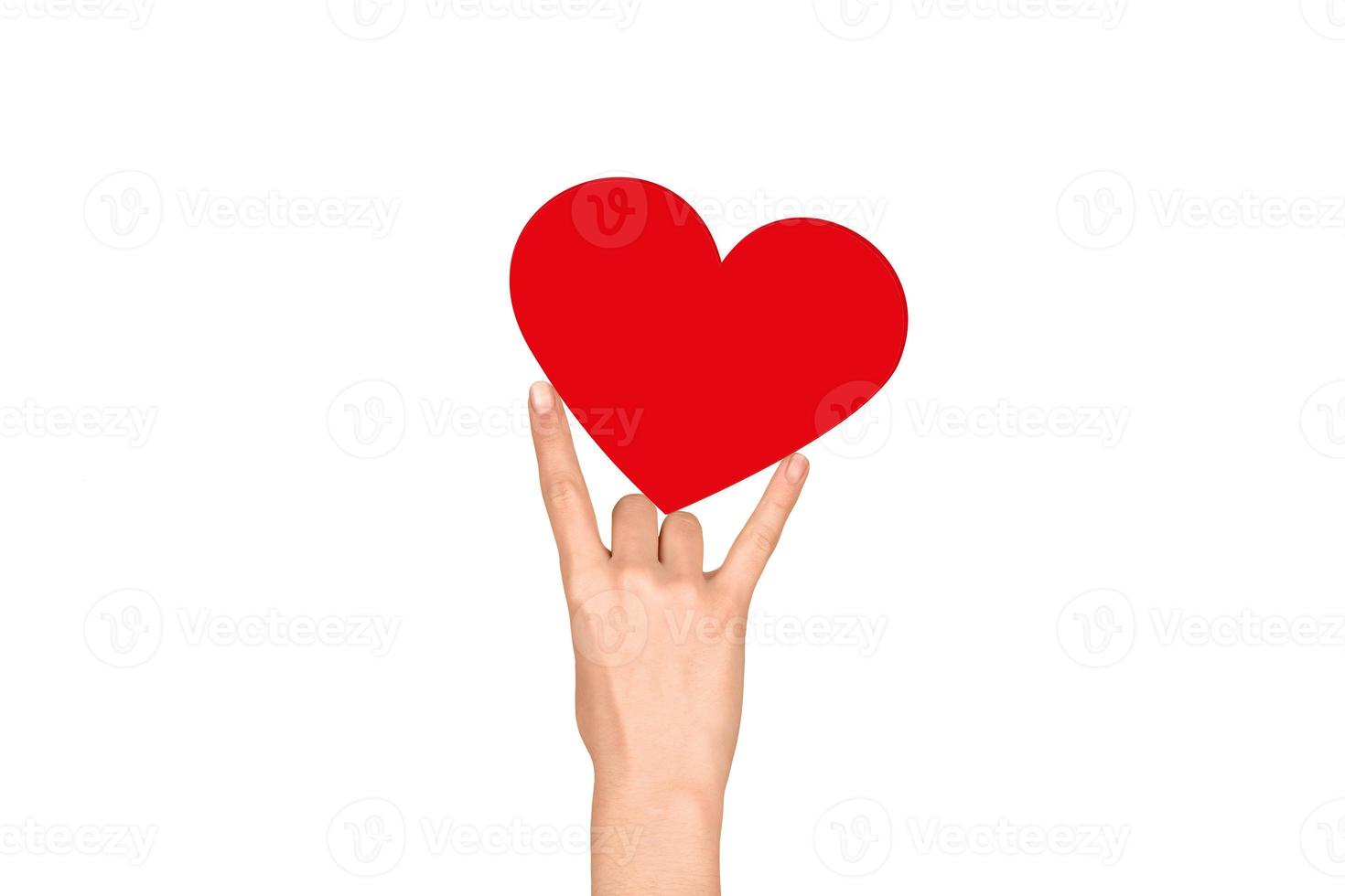 Red heart sandwiched between the fingers on a white background. Valentine's Day photo