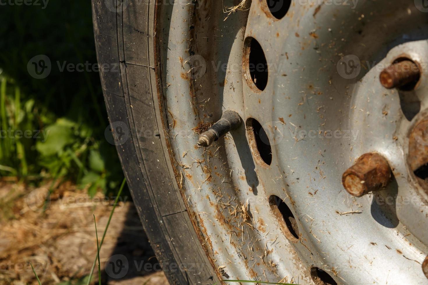 capped schrader valve and stem on a vehicle tire with rim. old rusty wheel in the sunlight. Close-up photo