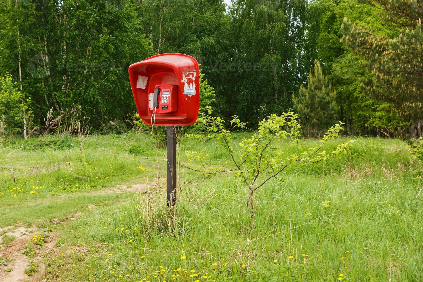 red Payphone standing in the field. Village telephone. Russia photo
