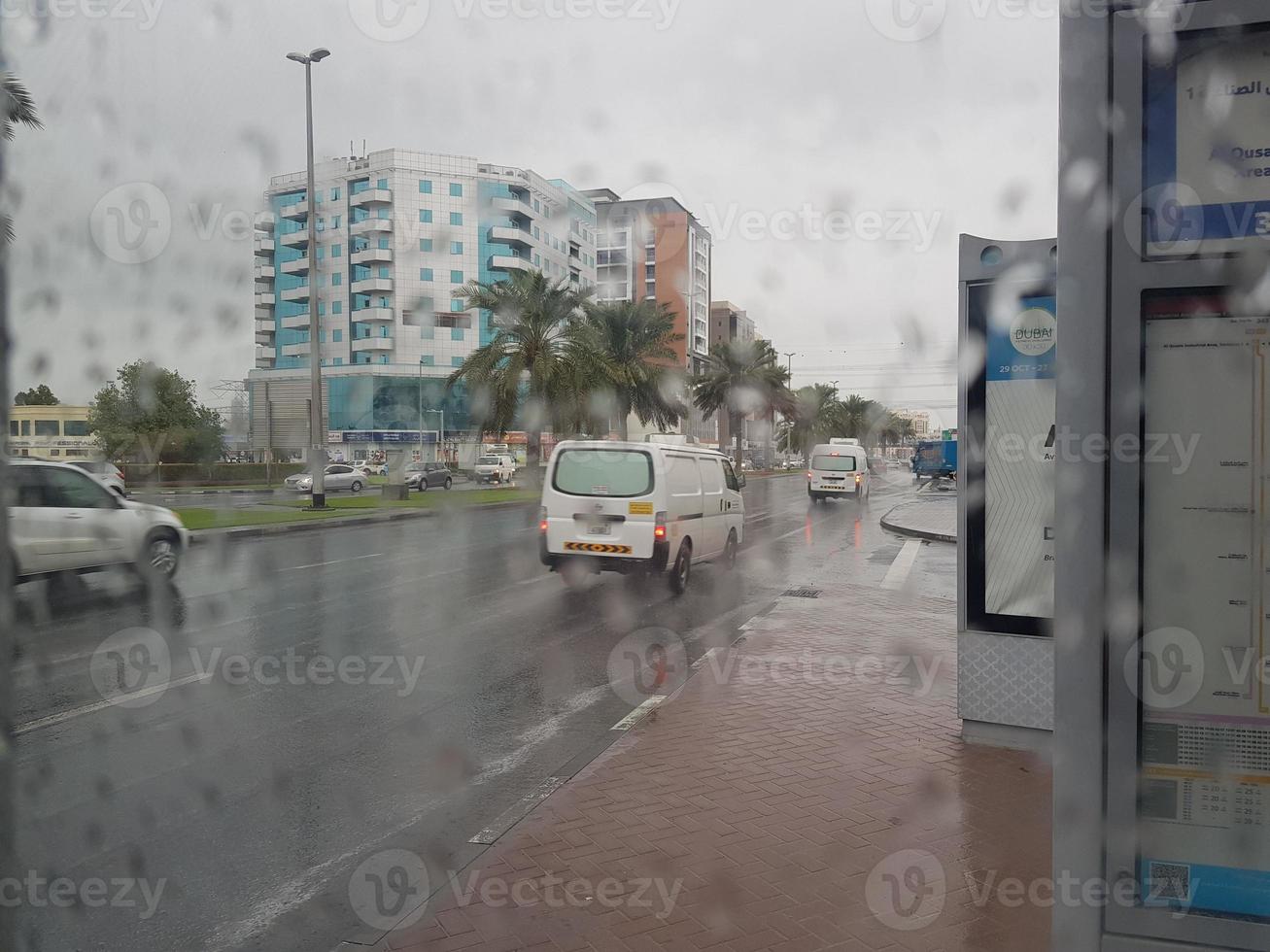 lluvia en los emiratos árabes unidos hermosa vista del lado de la carretera y sala de estar repartidor disfrutando en la lluvia bebé jugando silla hierba en la lluvia, el tráfico continúa en la carretera en un día lluvioso foto