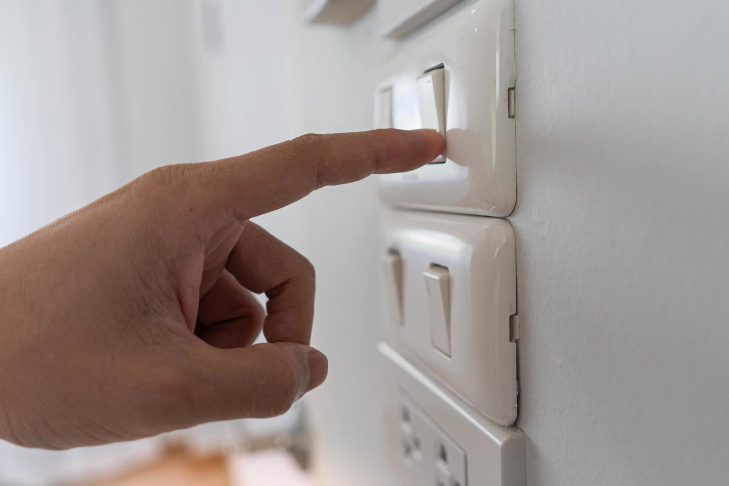 Ahorre electricidad, ahorro de energía y protección del medio ambiente. el dedo del hombre presiona el botón para apagar la luz. uso economico de la electricidad foto