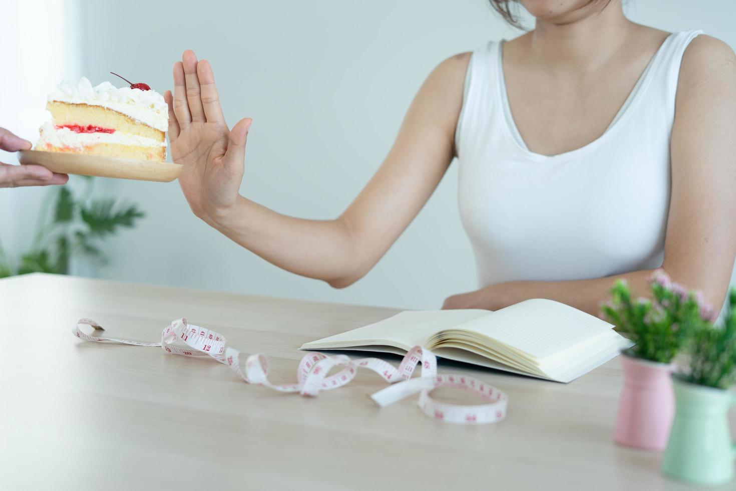 manos envía un plato de pastel a mujeres delgadas. la mujer empujó el plato de la torta y se negó a comer dulces y grasas. concepto de dieta y cuidado de la salud de las personas foto