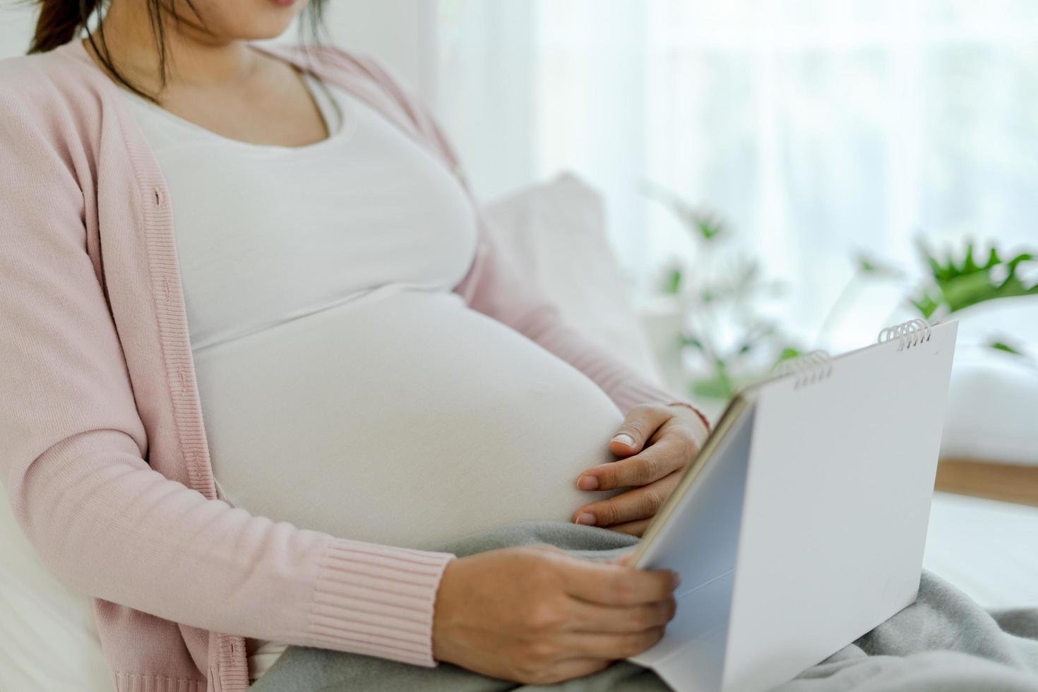 la mujer embarazada mira el calendario para la fecha de vencimiento del parto. la cesárea es una forma para que las embarazadas sepan una fecha de parto. preparar, recién nacido, desarrollo, monitor, cita, licencia de maternidad, edad gestacional foto